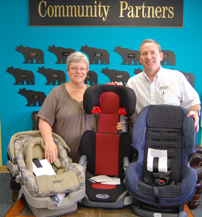 Community Connections' Patti Larson poses with Randy Driediger of Trees for Tots and some of the 16 car seats they helped purchase with a $500 donation to a BCAA Traffic Safety Foundation program that matched their donation to help needy families acquire car seats. David F. Rooney photo