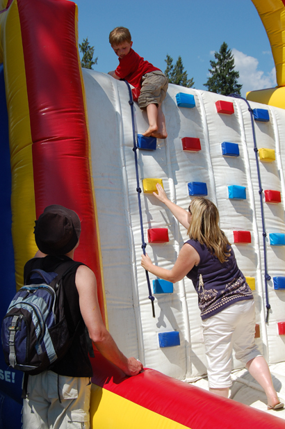 Mary Kline helps young Chaz Zaldo of Kamloops make his way down the inflatable climbing wall at the children's obstacle course set up at Queen Elizabeth Park as his father, Jose, watches. David F. Rooney photo