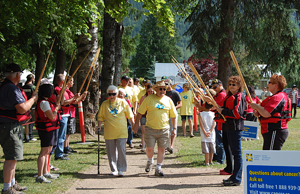 Cancer survivors march beneath the locally traditional arch of paddles hoisted by members of the Lake Revelstoke Dragon Boat Society, which counts as members many survivors of breast cancer. David F. Rooney photo