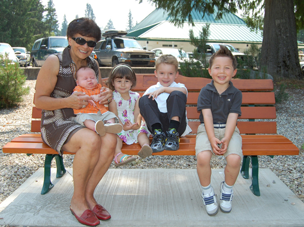 Anna Patchett sits on the bench dedicated to her late husband, Ron, with his grandchildren (from left to right) baby Alex Patterson, his big sister Mya, cousin Quintin Patchett and Ron's grand nephew Jacob Kehtler. Ron was a long-time teacher and coach at Revelstoke Secondary School whose premature death earlier this year was mourned by scores of former students.  The bench was erected near the Revelstoke Golf Course Clubhouse. David F. Rooney photo