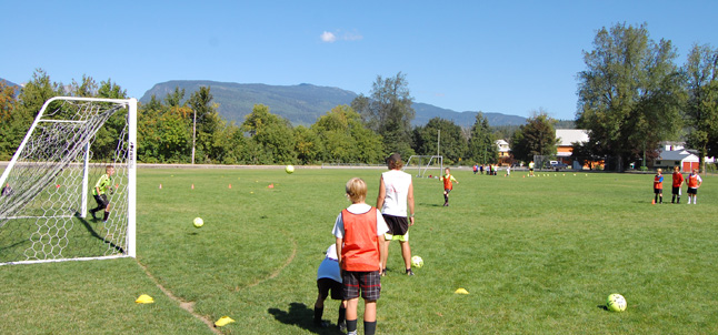 A British Football Camp coach watches as local kids practice some of the moves they taught them this week. David F. Rooney photo