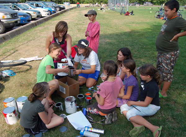 Cali Olleck left, center, (in the green T-shirt) gets a helping hand from a friend after she poured paint into a can held by fellow Pre-Teen Camp Counsellor Erica Maltby (center in the white top and blue shorts) as several of the kids in the camp looked on. The group planned to paint a number of City fire hydrants with colourful designs and their first one was at RSS. (See the photo below to see how it turned out). David F. Rooney photo