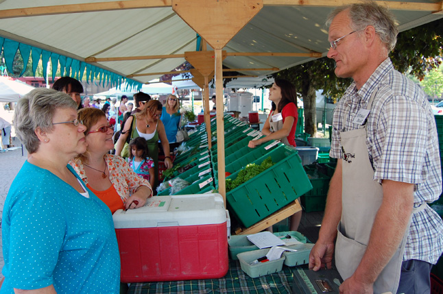 Community Connections' Patti Larson (center left) took Paula Luther (left), manager of the BC Association of Farmers' Markets' coupon project, on a tour of the Revelstoke Farmers' Market that included a chat with organic farmer Herman Bruns (right) last Saturday. Although regarded as highly successful, the project may not receive funding from the province next year. David F. Rooney photo 