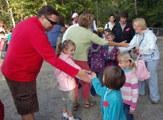 Gary McLaughlin slaps hands with a child at the start of the Kokanee Fish Festival at Bridge Creek. Slapping hands (the way fish might slap their tails) is a traditional opening to the day-long event. Organized by Mount Begbie Elementary School teacher Linda Dickson, the nine-year-old festival introduces local school children to red fish and the environment. David F. Rooney photo