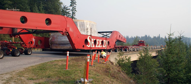 A worker peers beneath the massive transporter carrying BC Hydro's Unit 5 turbine as it negotiates the sharp curve at the head of the Westside Road bridge ovefr the Jordan River. Dusty Veideman photo courtesy of BC Hydro 