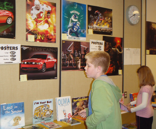 Spencer Brooks seems interested in the posters for sale at AHE’s annual Book Fair. Besides lots of books, posters and other things to buy, students had a chance to enter a draw to win $25 worth of books for their class and $25 worth of books for their family. Photo by AHE student photographer Jacqueline Cottingham