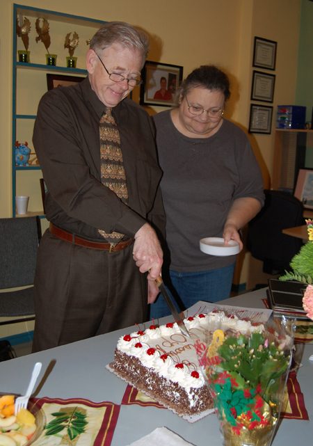 Peter Waters cuts the cake at the Revelstoke Awareness and Outreach Program's Fourth Anniversary Party Thursdy as Linda Streeter waits for a slice. David F. Rooney photo