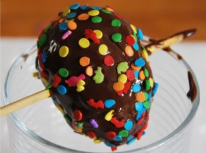 The trick to decorating chocolate eggs is to skewer the egg neatly right through the very centre, and let the skewer ends rest on a glass to dry after you swirl the egg in the melted chocolate and add the sprinkles.