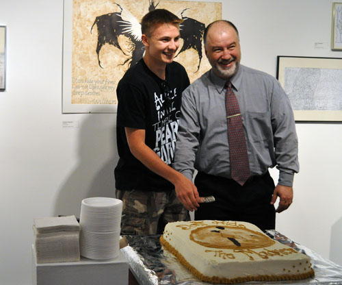 Student Alex Sarr and Principal Greg Kenyon cut the cake that opened the school's exhibition of 71 works on Friday evening. David F. Rooney photo