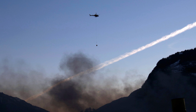 A helicopter with a bucket flies towards the fire. Photo by anonymous