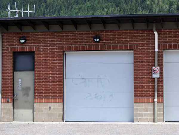 A local youth was arrested last Saturday for vandalizing five buildings and several vehicles with yellow and blue paint. According to RCMP Cpl. Thomas Blakney the youth, who may have had some confederates, painted “Grad 2013” and “Hi Grad 2013” as well as vulgar images, some type of signature and paint smears on a stop sign, the Community Centre, the Fire Hall, the RCMP detachment, the Post Office and Coopers.  The acts of vandalism occurred in the pre-dawn hours. The youth was arrested that evening.“The RCMP are continuing to investigate these deliberate acts of vandalism and hold the culprit accountable,” Blakney said. “I would like to stress that this senseless act was caused by a few bad apples and certainly should not place a negative stigma or tarnish the graduating class of 2013.”  Most of the graffiti, like this one scrawled on the RCMP detachment's garage door, has been painted over. David F. Rooney photo