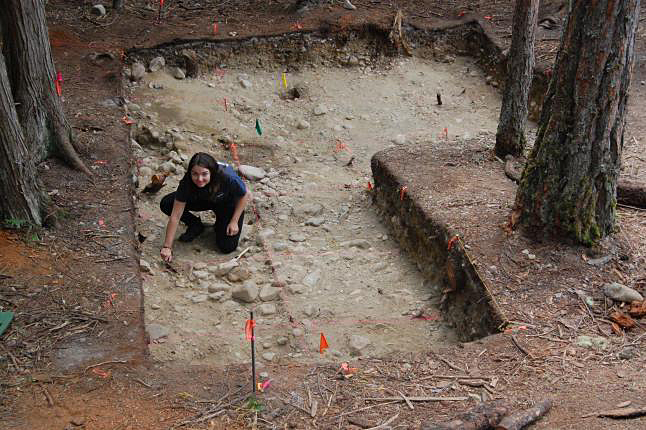 LEMON CREEK — Archaeology student Morgan Biggs demonstrates the use of tools to gently explore the floor of the pithouse. Each student is assigned a square metre to study. Biggs and her classmate Max Lopez explain that that the inhabitants kept their pithouses very clean, possibly throwing debris into the river. This fact, combined with the acidity of the soil which decomposes items like fish bones, means that there isn’t as much material left to study as might occur at other archaeological sites. Laura Stovel photo 