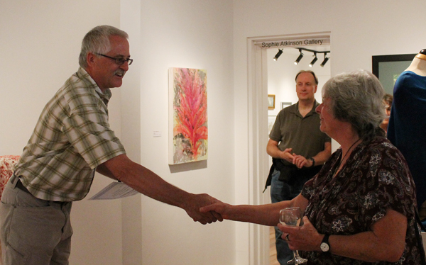 Visual Arts Society Chairman shakes hands with artist and volunteer Eve Fisher as he presents her with a certificate of appreciation for her work on the art gallery's flooring project. Jewelles Smith photo