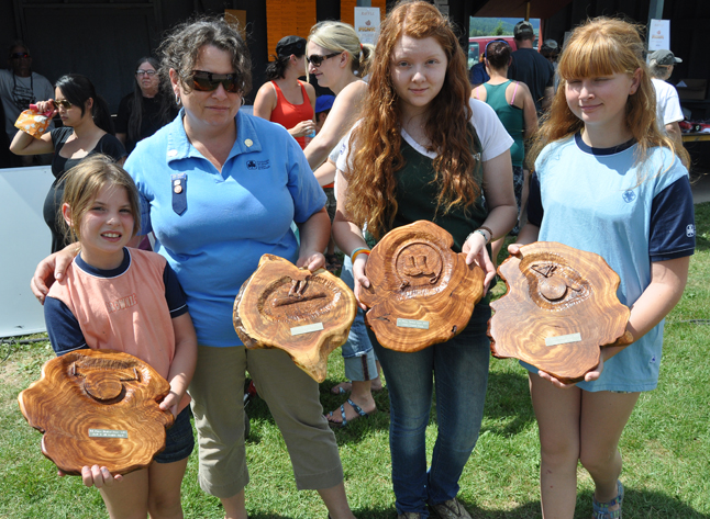 Lisa Moore, Halle Simpson and Lauren and Sara Channell display some of the gorgeous carved trophies created for this year's Timber Days by master carver Rod Aspeslet. David F. Rooney photo