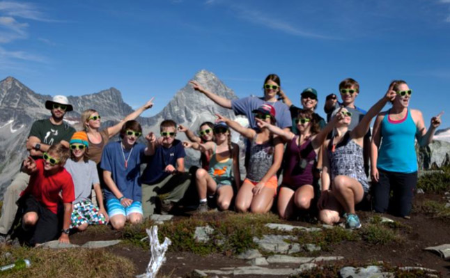 Photographer Natalie Harris takes a group photo of GASP students and leaders wearing their Stoked Youth Network glasses at the top of Abbot Ridge. (Back L to R) Matt Keeler, Megan Shandro, Emma Knight Flood, Marie Busch, Alice Weber, Gordon Mason, Laura Kanik. (Front L to R) Wyatt Callaghan, River Kelly, Charlie Sykes, Mackenzie Mallet, Sara Howatt, Anne-Marie Duchesne, Maxine Opatril and Alexis Allain.  Natalie Harris photo courtesy of Parks Canada