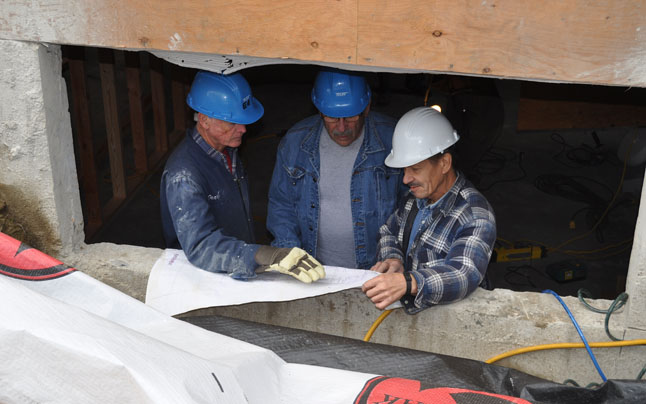 Ed McLean, Harri Munschler and Jerry Heickel use an open basement window to go over the plans. David F. Rooney photo