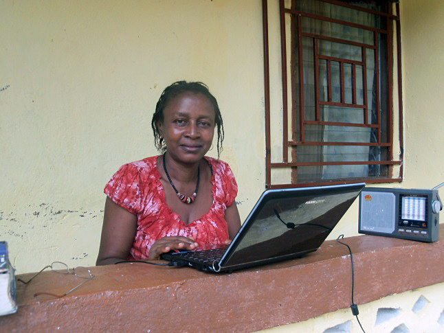 Manty listens to her radio as she works on her laptop. Photo courtesy of Manty Dabo