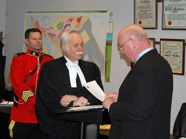 Robert Lundberg administers the oath of office to Mark McKee as RCMP Staff Sgt. Kurt Grabinsky looks on. David F. Rooney photo