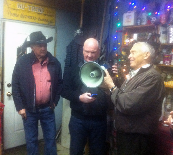 Mark McKee and Geoff Battersby (right) try to figure out how to use a megaphone to deliver a holiday message Premier Christy Clark sent to Peter Bernacki via cell phone on Thursday, December 4. Peter (left) is a vice-president of the BC Liberal Party Constituency Association and wanted guests at his annual Christmas garage party to hear the premier's message. It took a few minutes but Mark and Geoff eventually got it to work. David F. Rooney photo