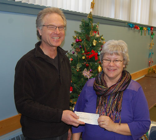 Ken Jones, chairman of the Bygone Era Entertainment Society, hands Patti Larson, director of the Community Connections Food Bank, a cheque for $310 that the society raised from its Grand Victorian Christmas Magic Lantern Show last week. David F. Rooney photo