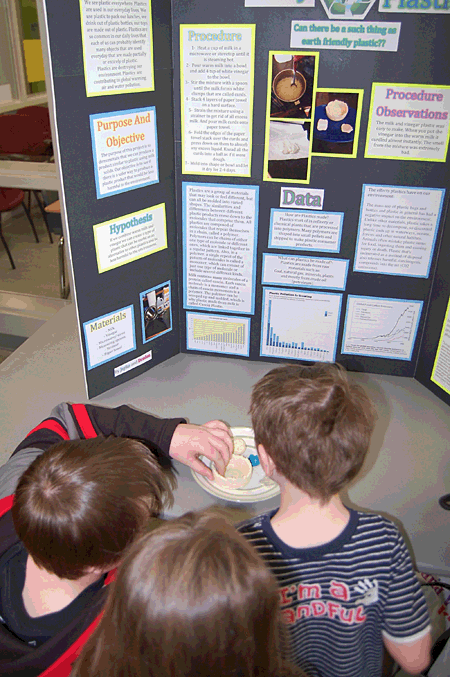 Children from you get grades toured the Grade 7 class's displays in the lobby at Begbie View all morning on Wednesday. Here they examine the properties of plastic in Drayden Williams and Jayke Coueffin's experiment. David F. Rooney photo