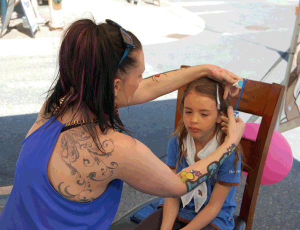 Face painter Tina Schults pins back young Madeline Hunt's hair. Then she asked what kind of face painting the youngster wanted. A pussy cat. And what colour would she like the cat to be? Blue. Then Tina set to work... David F. Rooney photo
