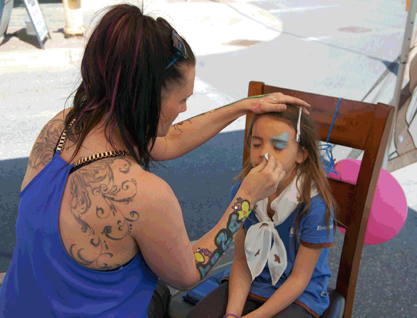 Using firm but gentle strokes Tina smears light blue paint on Tina's face and brow. David F. Rooney photo