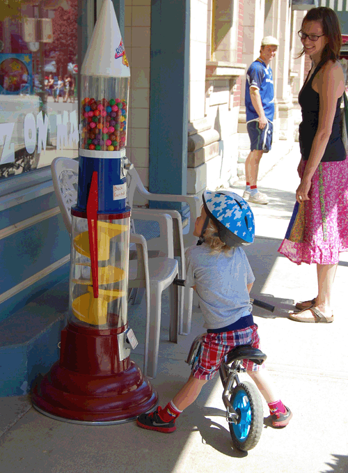 "What's that, Mommy?" asks young Fionn Kelly of Kristin Olson as they meandered down Mackenzie Avenue on the Saturday. Clearly, this youngster had never seen a gumball machine before. Fortunately, this candy rocket may be the only one in Revelstoke. Long ago, when I was Fionn's age you couldn't go to a supermarket in most towns and cities without running a gauntlet of mechanical candy dispensers and nickel rides on rockets and horses, fire trucks, police cars and what-not. My mother was not a fan of these mechanical bandits and used the word "No" to good effect. David F. Rooney photo