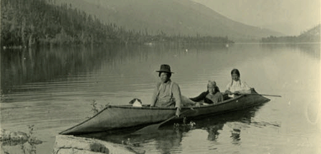 A native family approaches a lakeshore in a traditional sturgeon-nosed canoe smite in the early part of the last century. Photo courtesy of the Columbia Basin Trust