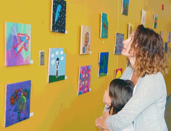 Tracy Hill and her daughter Charlie gaze at some of the scores of paintings made by students on display at RSS for the official unveiling of the Aboriginal education program's gorgeous mural. David F. Rooney photo