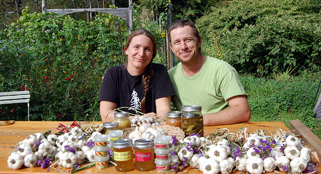 Call it what you will — ajo, ail, knobi, bulblet, arishtha, Allium sativum or even the stinking rose — garlic enlivens your palate and your health. Just ask Sarah Harper and Stuart Smith, posing here with some of what's on offer this Saturday during the Second Annual Revelstoke Garlic Festival, which they are hosting at their property on Track Street East. David F. Rooney photo