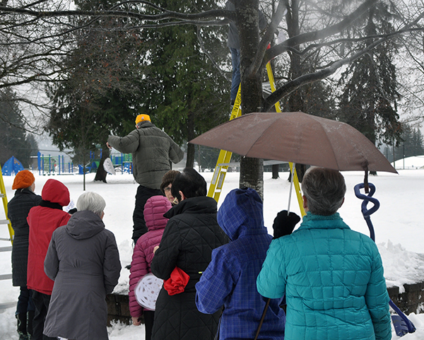 Snowflakes in hand, participants in the ceremony wait their turn to hand their snowflakes, each bearing the name of someone who has gone from this world, to Jack O'Brien and Fred Olsson who teetered on ladders to hang the snowflakes. David F. Rooney photo