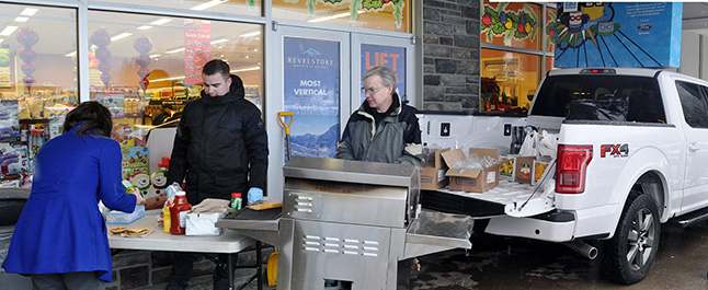 Cody Younker (left) and Rob Bett served up burgers for hungry customers at Cooper's and also took custody of donations for the Food Bank during the Stack the Back drive. David F. Rooney photo