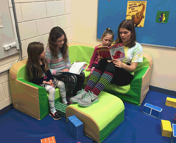 From Left to Right: Lily Schott, Ava Keerak, Collins Creighton, and Sam Brown read together at Red Wagon Preschool at Arrow Heights Elementary School. Photo by Monica Degerness. Caption by Emily MacLeod, Amelie Delesalle and Rebecca Grabinsky