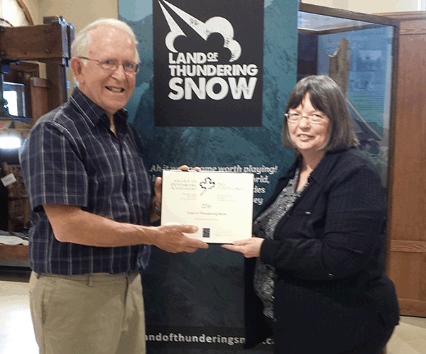 John Woods, researcher and writer of Land of Thundering Snow, poses with Cathy English and the Canadian Museums Association Award for Outstanding Achievement. Photo courtesy of the Revelstoke Museum and Archives
