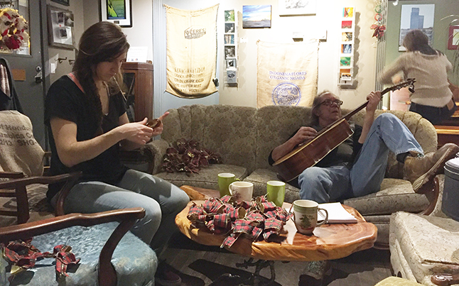 Jess Oundjian (left) works on Christmas ornaments while Bob Gardali kicksbak with a guitar, while Sangha Bean Cafe proprietor Krista Cadieux (right background) hangs sesaonal decorations. David F. Rooney photo